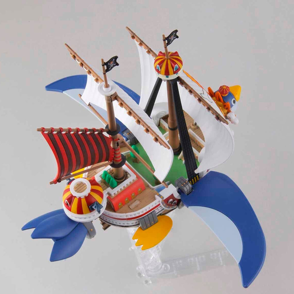 Model ship with colorful sails and flags on a gray background