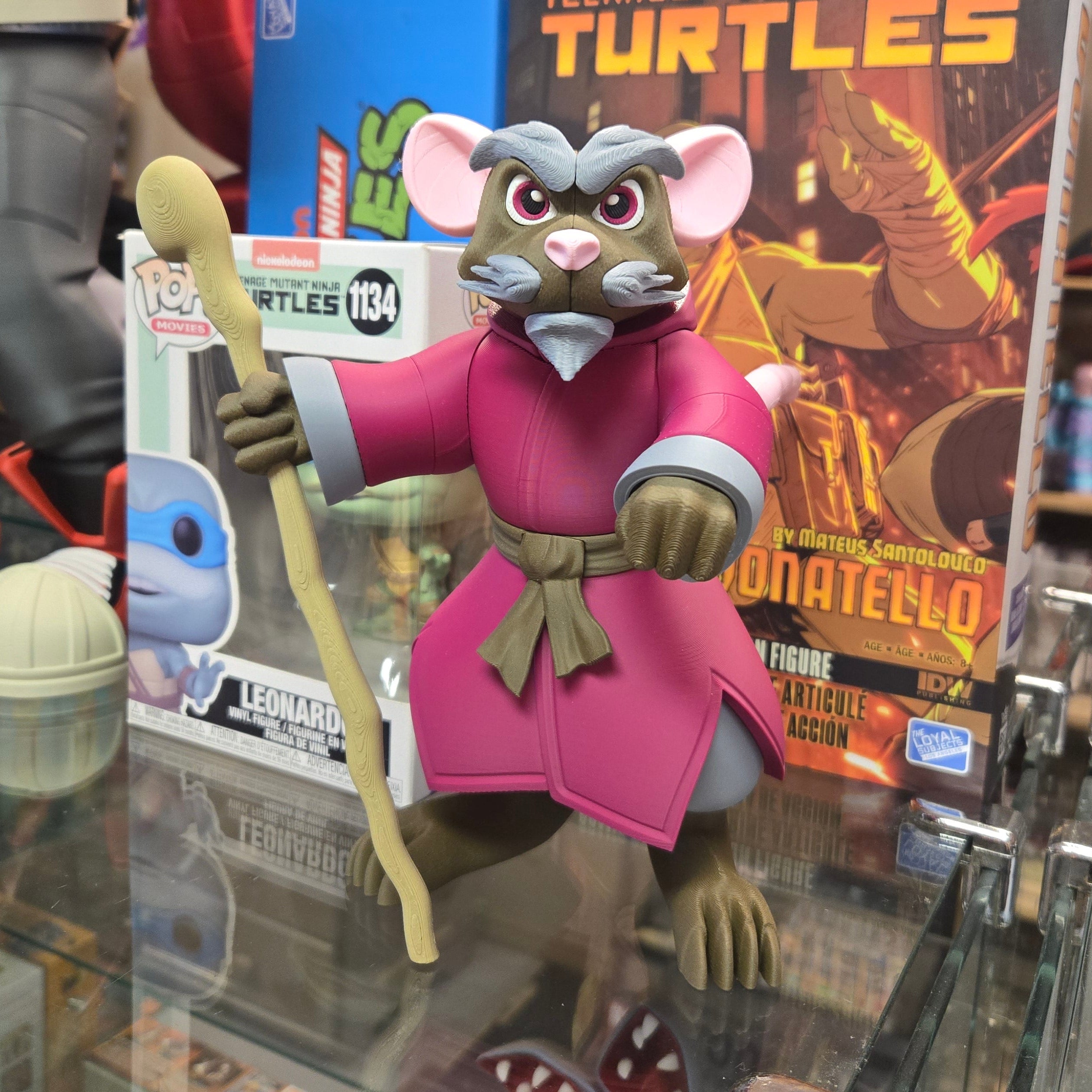 Action figure with pink and gray outfit in front of a Teenage Mutant Ninja Turtles book
