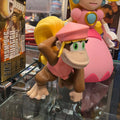 Toy figure of a character with a pink dress and yellow hair in a glass display case.