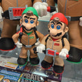 Toy figures of characters from a video game, with packaging and other items in the background.