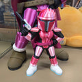 Pink and purple action figure with a weapon on a reflective surface