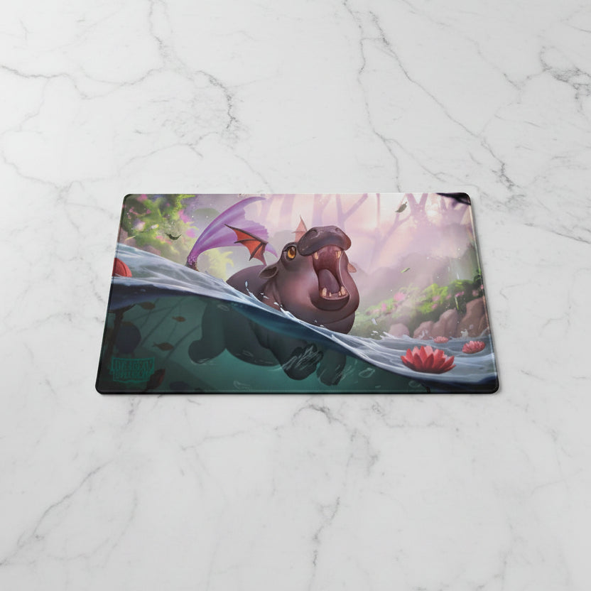 Fantasy illustration of a hippo-like creature with purple wings rising from water, surrounded by lotus flowers and a misty forest background. A visible artist signature/watermark appears in the lower-left corner.