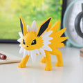Yellow and white figurine on a desk with a tablet and mug in the background