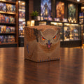 A cube-shaped box or container printed with a detailed illustration of an owl's face and feathers in shades of brown, tan, black, and bright orange eyes, shown on a plain white background.
