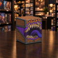 A stylized illustrated monster chest with a wooden front, dark metal corners, glowing orange eyes on top, a wide open mouth with large beige teeth, and a purple tongue and purple underbelly, shown on a plain white background.