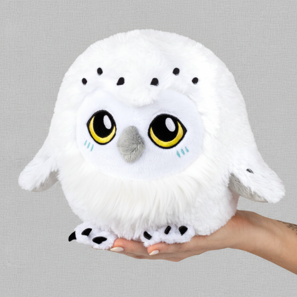 White plush owl toy held in a hand against a white background