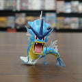 Toy figure of a blue and yellow creature with large mouth and spikes on a white background