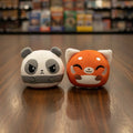 Two plush toys, one panda and one red panda, on a gray background