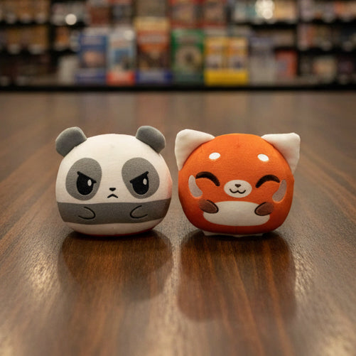 Two plush toys, one panda and one red panda, on a gray background