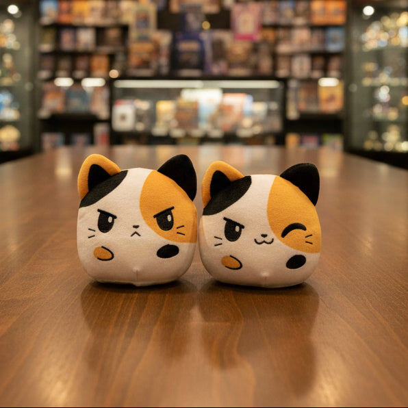 Two calico cat-shaped plush toys on a gray background